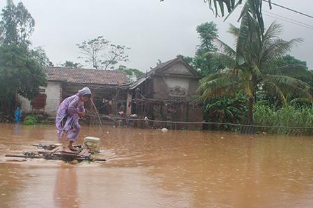 Một em nhỏ ở xã Quảng Hải chóng bè đi lấy nước sạch trước khi lũ tràn vào nhà.