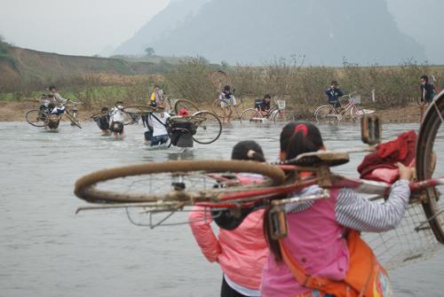 Học sinh phải cõng xe đạp đến điểm nước nông trên sông Nan để lội về nhà (Trang thông tin điện tử Văn phòng UBND tỉnh Quảng Bình)